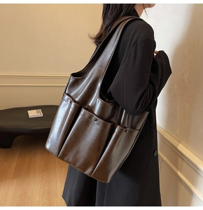 Detail of a deep brown faux leather tote bag with multi-pocket design on the side
