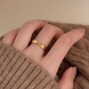 Macro shot of gold twisted rope ring on a warm sweater background showing polished finish