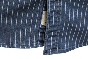 Detailed macro view of heavy washed striped denim shirt side seam and quality label