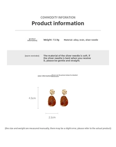 Detail view of irregular amber resin drop earrings with golden textured alloy tops
