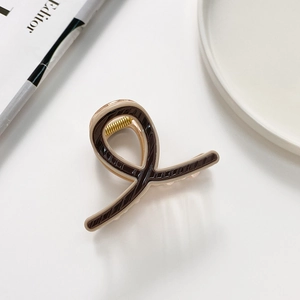 Detail of twisted X-shape hair claw clip in brown and beige stripe texture finish