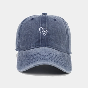Detail of double heart embroidery on washed denim fabric of a vintage baseball cap