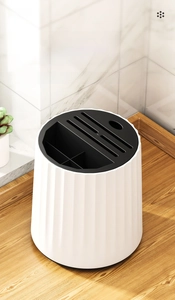 Close-up of a white cylindrical kitchen knife holder with multi-slot black top cover