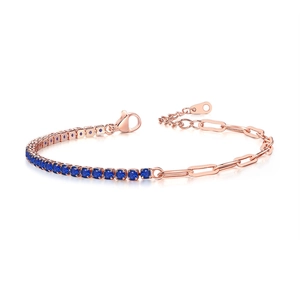 Detail of rose gold tennis bracelet featuring blue cubic zirconia and paperclip chain link