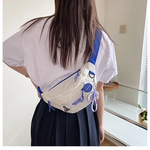 Close-up of white canvas chest bag featuring blue straps and a cute purple bear charm