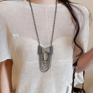 Sparkling bow pendant with long layered tassel chains on white knit sweater