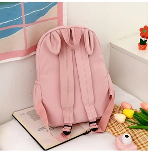 Rear view detail of a pink rabbit ear backpack featuring soft nylon texture and straps
