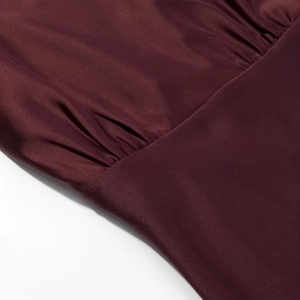 Detaillierte Nahaufnahme von weinrotem Satinstoff mit Plissee-Design und feiner Textur
