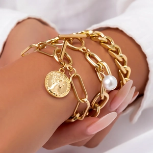 Detailed close-up of gold coin pendant and pearl bracelet set on a woman's wrist