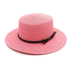 Close-up of pink woven straw hat detail with black band and bronze arrow hardware