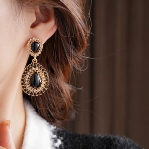 Gros plan de boucles d'oreilles vintage en or avec pierres noires sur un mannequin
