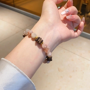 Detailed shot of amethyst and quartz beaded bracelet on wrist with silk sleeve background