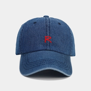 Close-up of red 'R' letter embroidery on a navy blue denim baseball cap detail