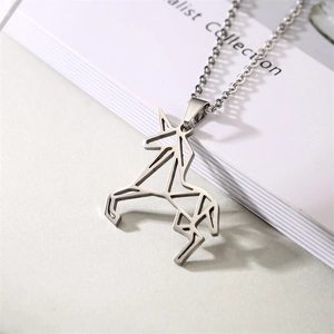 Détail d'un collier avec pendentif licorne géométrique en acier inoxydable argenté sur un livre