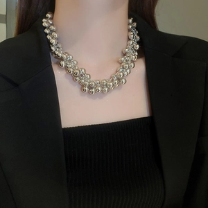 Detail of high-shine silver bead choker necklace layered on a professional model