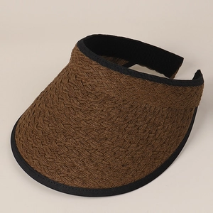 Detail of hand-woven texture and black ribbon edge on a brown straw sun visor hat