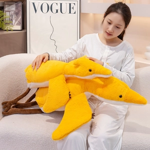 Close-up of a large yellow plush pterosaur pillow being held to show soft texture