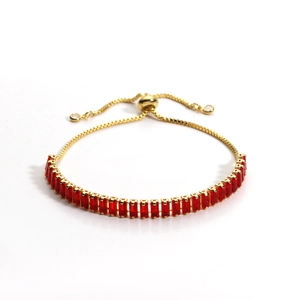 Detail of gold tennis bracelet with rectangular red zircons and adjustable slider clasp