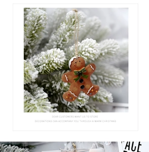 Detailopname van peperkoekman hangend aan besneeuwde dennentakken met witte glazuurtextuur