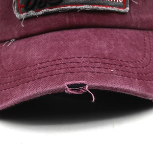 Macro detail of distressed brim and vintage patch on burgundy washed cotton baseball cap