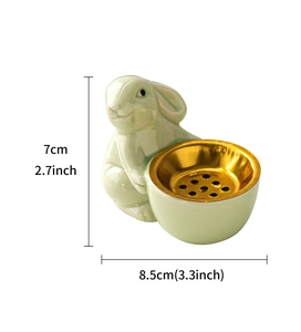 Detail view of a green ceramic rabbit aromatherapy burner with gold metal tea filter