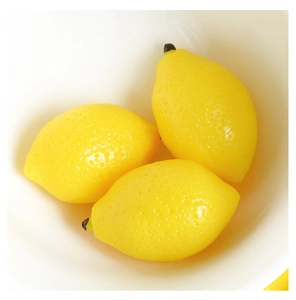 Detailed close-up of three artificial yellow lemons with realistic textured skin and stems