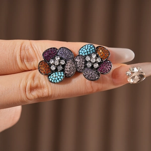 Macro shot of vintage flower earrings with colorful zircons on a model's finger
