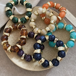 Detail of marble pattern resin beads and gold metal spacers on colorful elastic bracelets