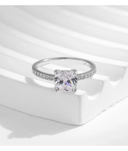 Macro shot of silver ring with large square white stone and side accent diamonds