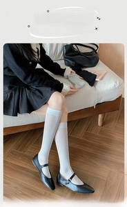 Close-up of white ribbed calf socks styled with black Mary Jane shoes and pleated skirt