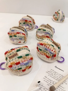 Detail of colorful knitted headphone case showing thick yarn texture and purple carabiner