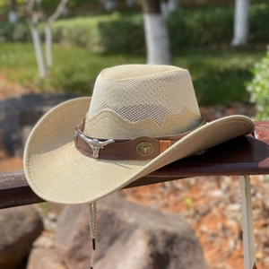 Beige straw cowboy hat with cow skull emblem and leather band on a wooden fence
