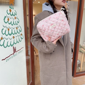 Trousse de toilette rose en coton matelassé avec motifs cerises tenue par un mannequin