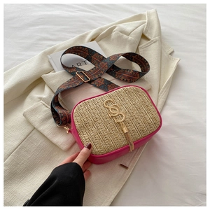 Close-up of woven straw bag with magenta leather trim and ethnic style wide strap