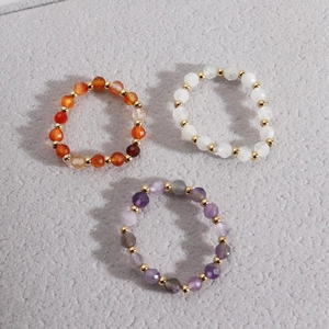 Detailed macro view of natural stone beaded rings with gold spacer accents and elastic band