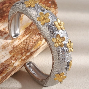 Macro shot of silver open cuff bracelet with gold flower relief on natural stone