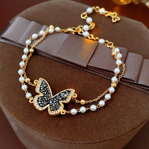 Detail of double-layer gold butterfly bracelet with pearls and crystals on velvet