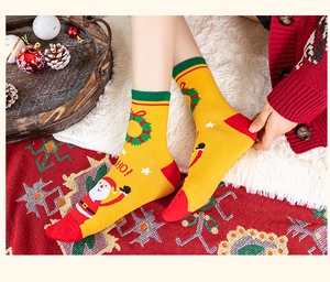 Detail of yellow Christmas mid-calf socks with Santa Claus patterns on a cozy festive rug