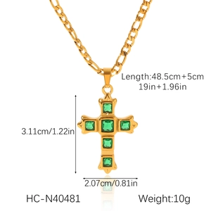 Detail view of a gold Figaro chain necklace with a green zircon-studded cross pendant