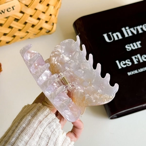 Handheld view of a large marble patterned acetate cat hair claw clip with spring detail