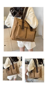Detail of a large brown canvas tote bag with dual front pockets and wide shoulder straps