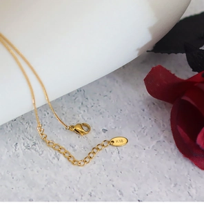 Macro detail of 18K gold-plated lobster clasp and adjustable extender chain on necklace