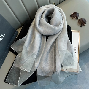 Detailed macro view of silver silk scarf with metallic luster on elegant black fabric