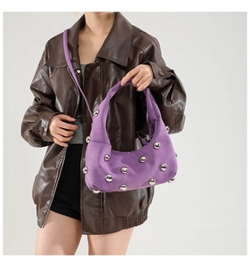 Detail of purple suede handbag featuring silver spherical metal studs and matte texture