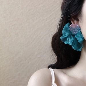 Détail du nœud en ruban bleu et de la rose en résine rose porté sur l'oreille
