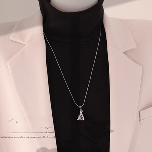 Silver money bag pendant necklace on snake chain styled with beige blazer