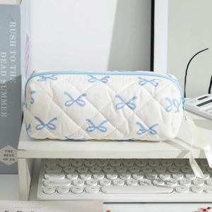 Close-up of quilted pencil case with blue bow patterns on a clean workspace desk