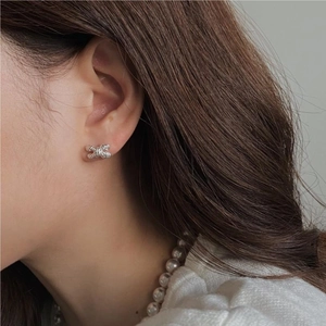 Detail of S925 silver knot earrings featuring a textured rope twist design on earlobe