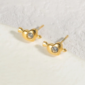 Golden heart arrow earrings with sparkling crystal stone on a textured stone surface