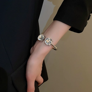 Close-up of silver open bangle with two large round cut crystals on female wrist